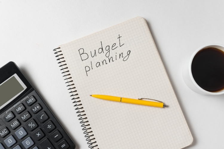 calculator, pen on notebook and cup placed on table