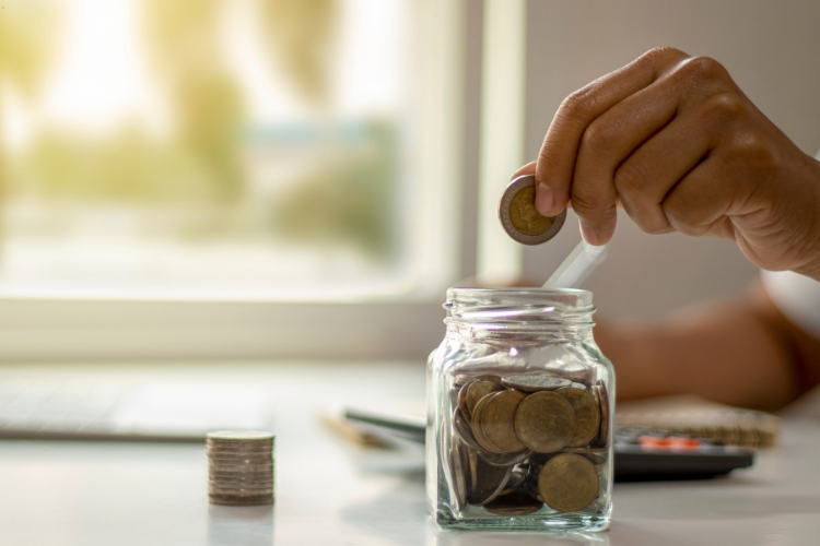 man putting coins in jar