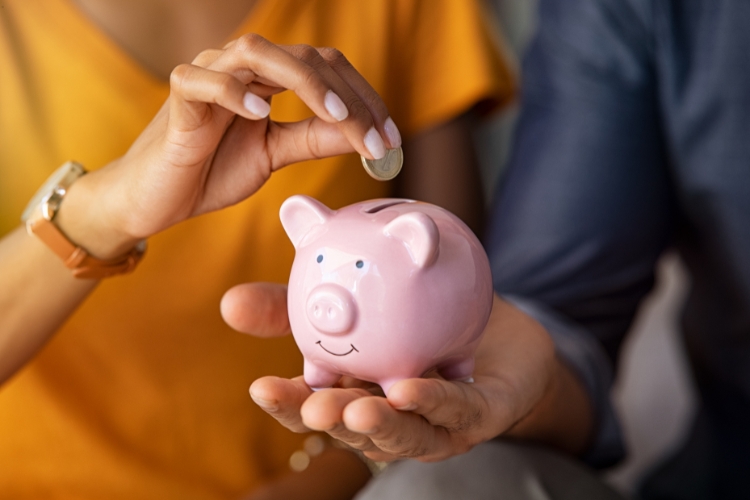 woman adding coin to money bank